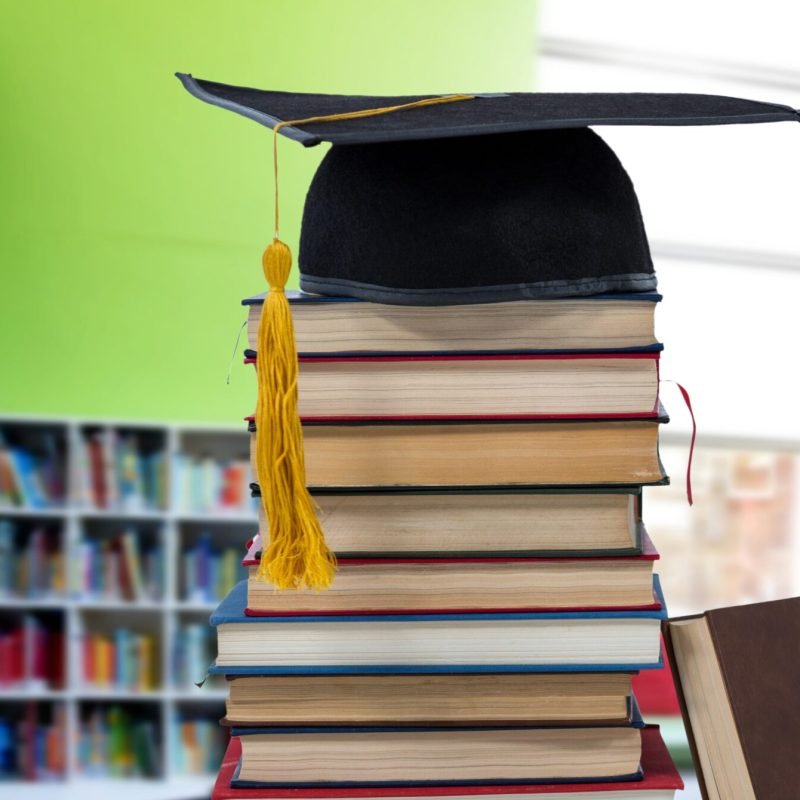 Digital composite of Books and graduation hat in education library